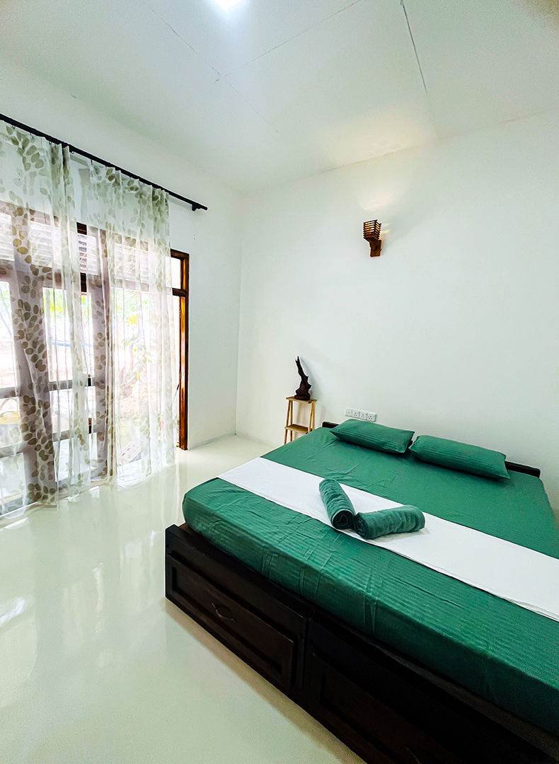 Non-AC room with wooden desk and clothes rack